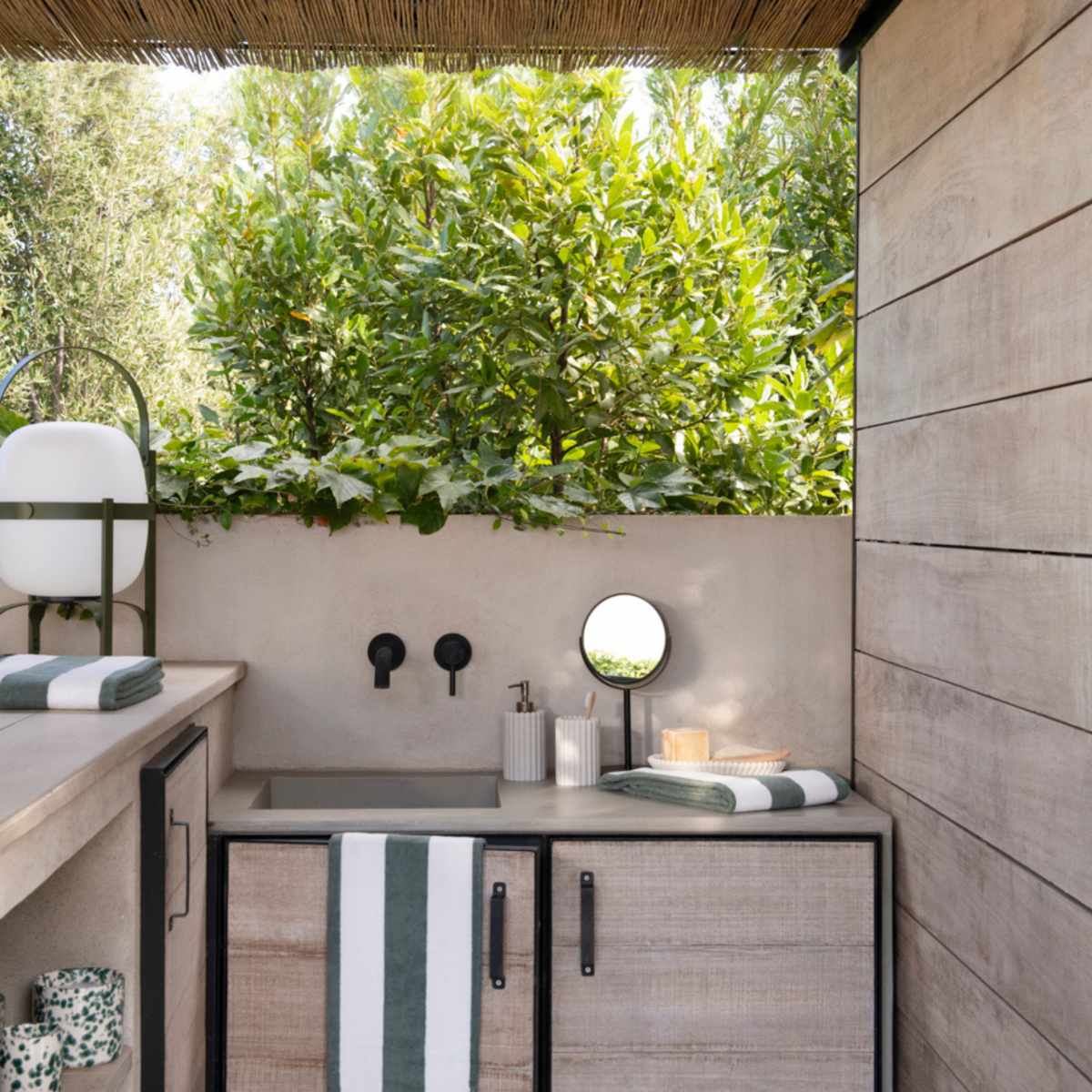 Baño exterior con dispensadores de poliresina con rayas beige.