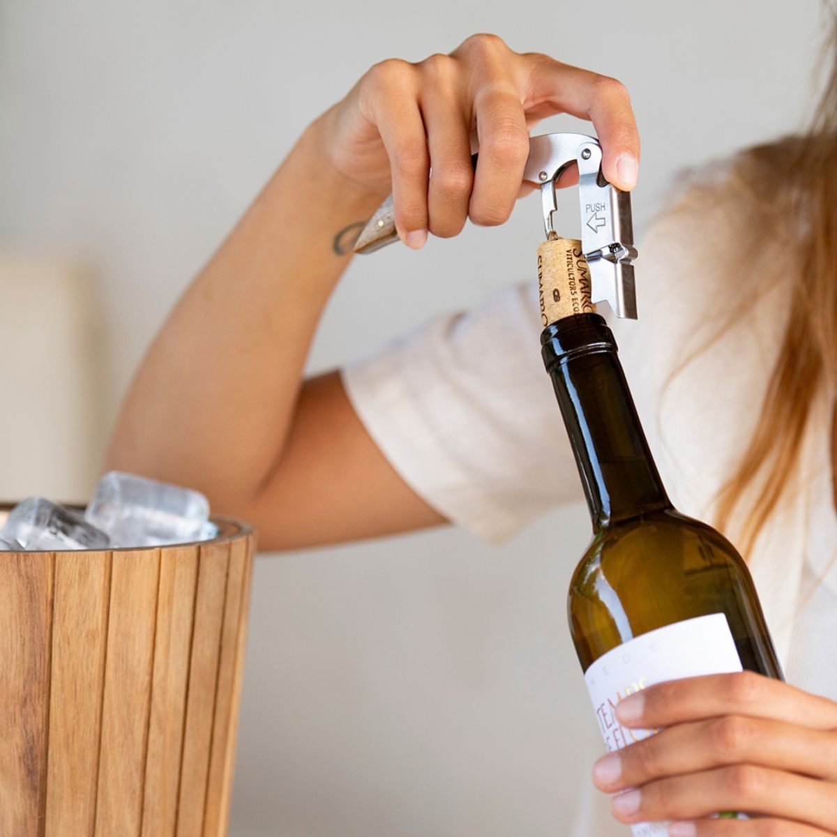 Sacacorchos de acero inoxidable con mango de madera en uso para abrir una botella de vino