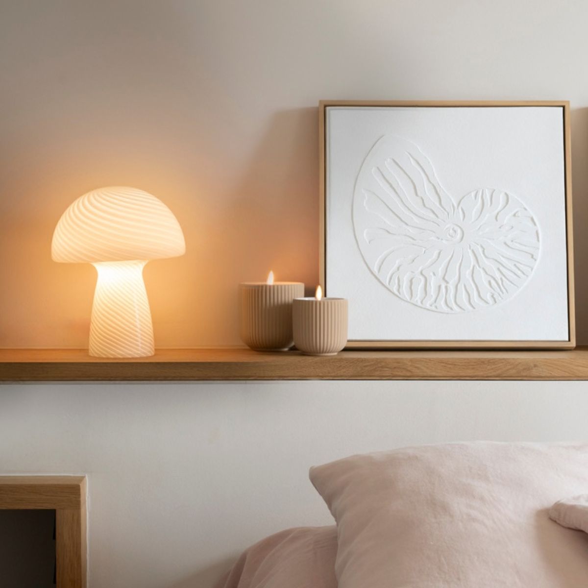 Lámpara de mesa blanca encendida sobre mueble de madera en dormitorio.