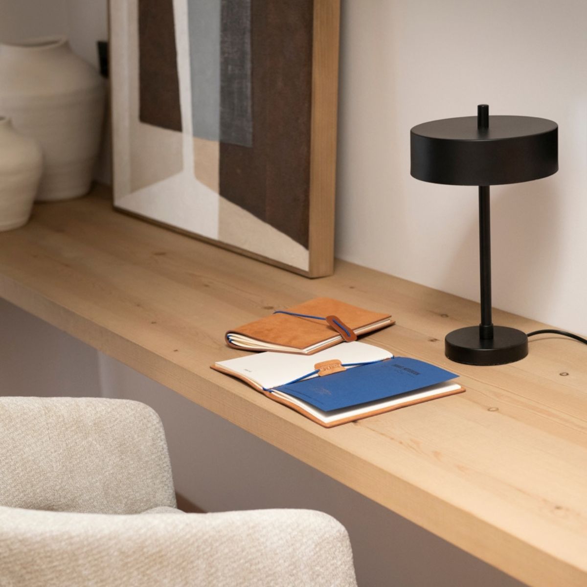 Lámpara de mesa negra sobre escritorio de madera en espacio de trabajo.